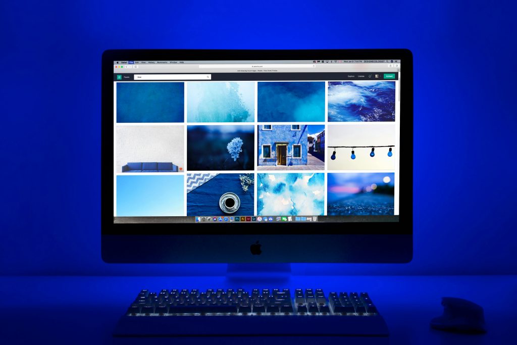 Modern workspace with a glowing blue theme and a computer monitor showcasing a gallery of images.